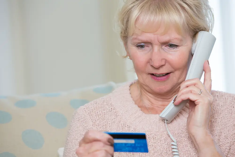 woman looking concerned talking to "grandchild" on the phone asking for money