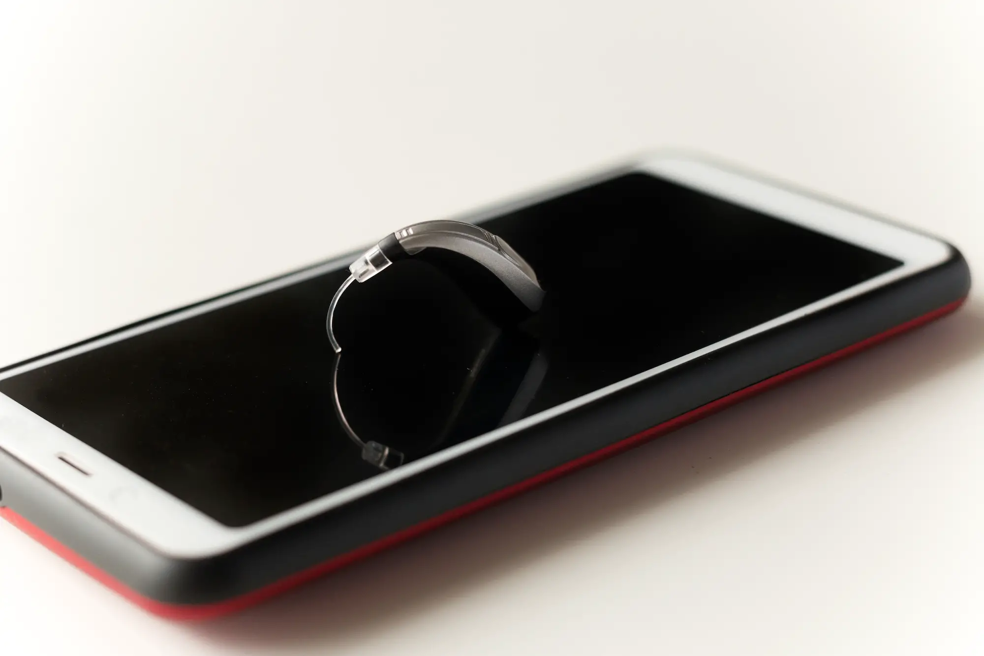 small modern hearing aid sitting on smartphone