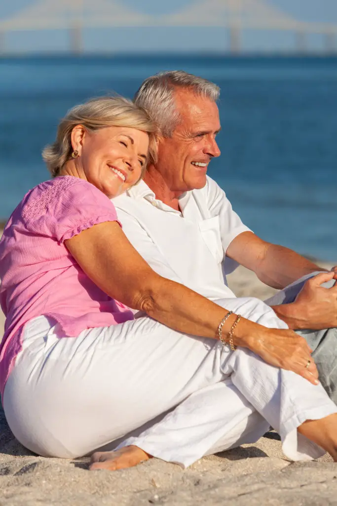 A happy senior couple sits on the beach.