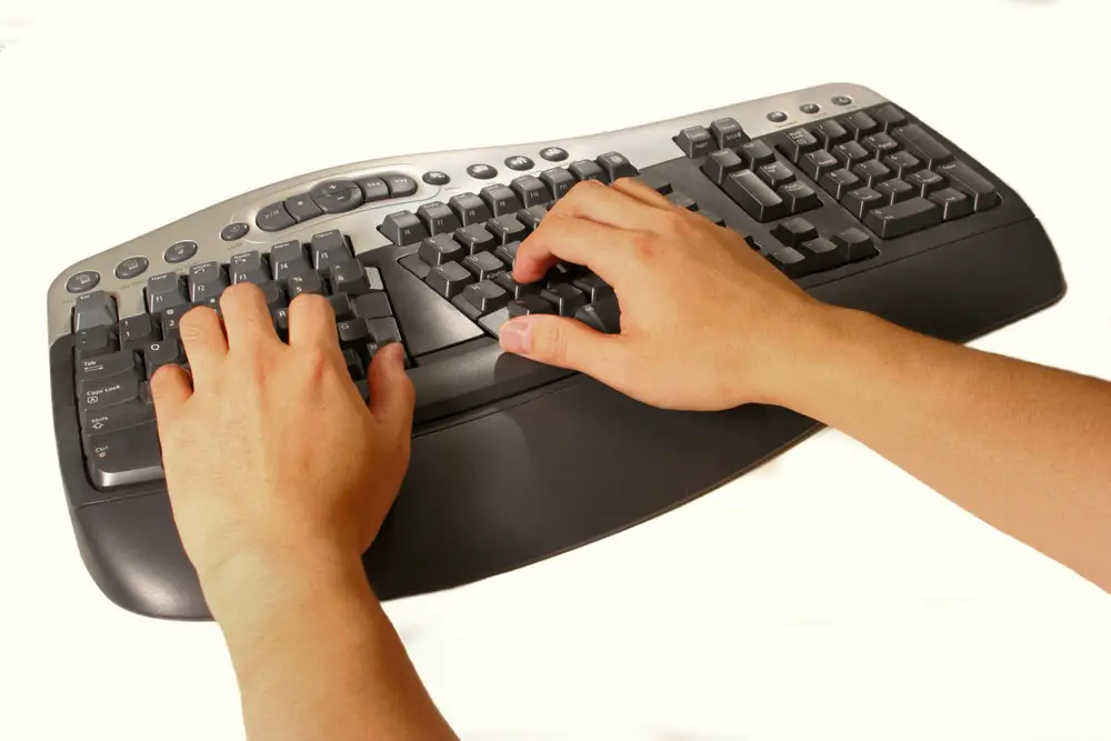 A pair of hands typing on a black ergonomic computer keyboard