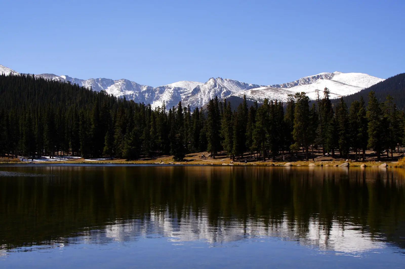 Echo Lake with mountains in the far background and evergreens framing a lake that reflects the trees, mountains and blue sky