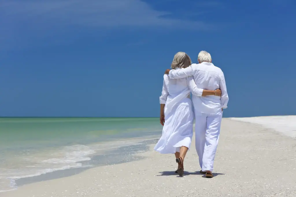A senior couple walks on a beautiful beach.