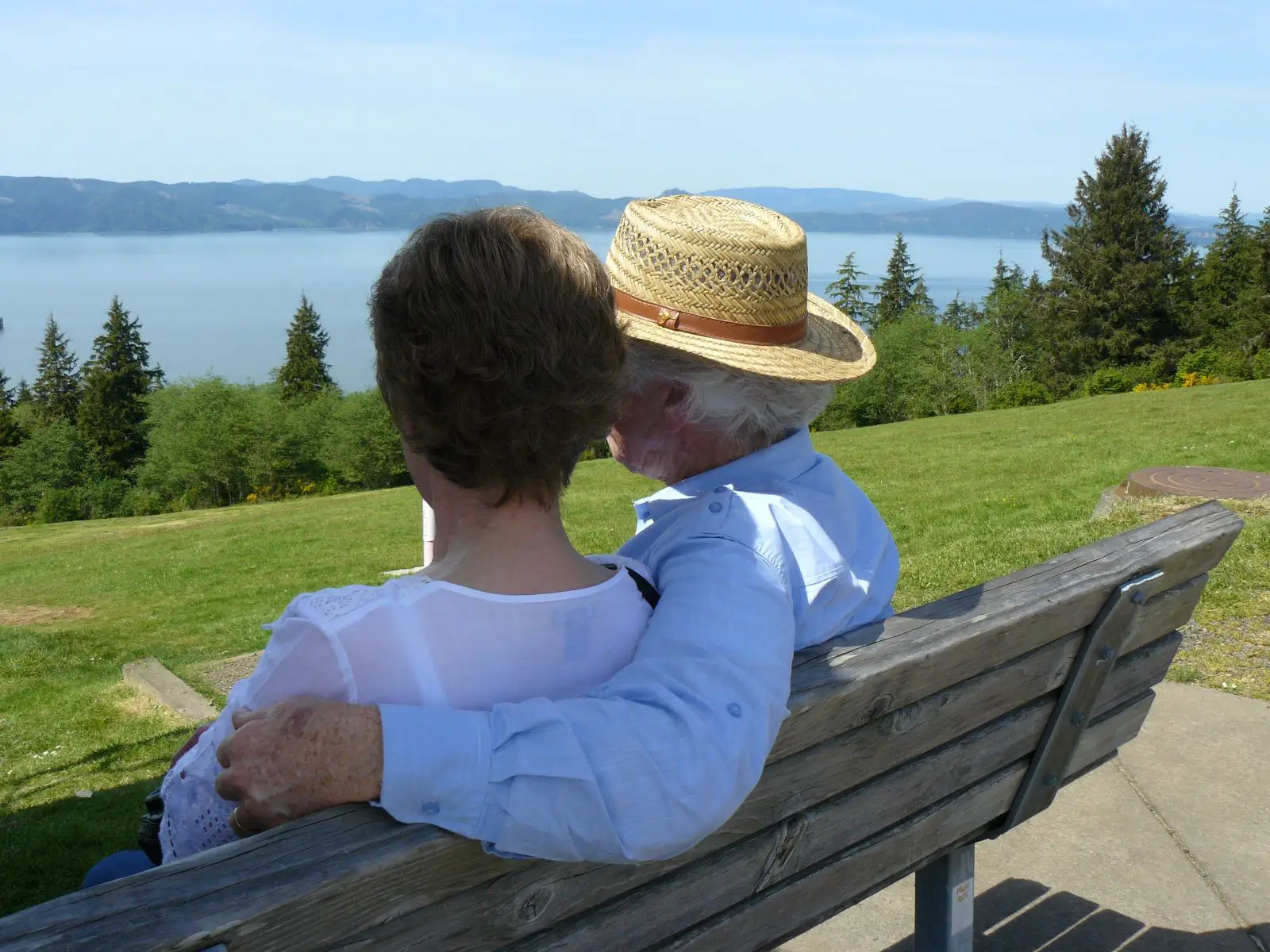 Senior couple sitting on park bench overlooking the Columbia River in Hood River