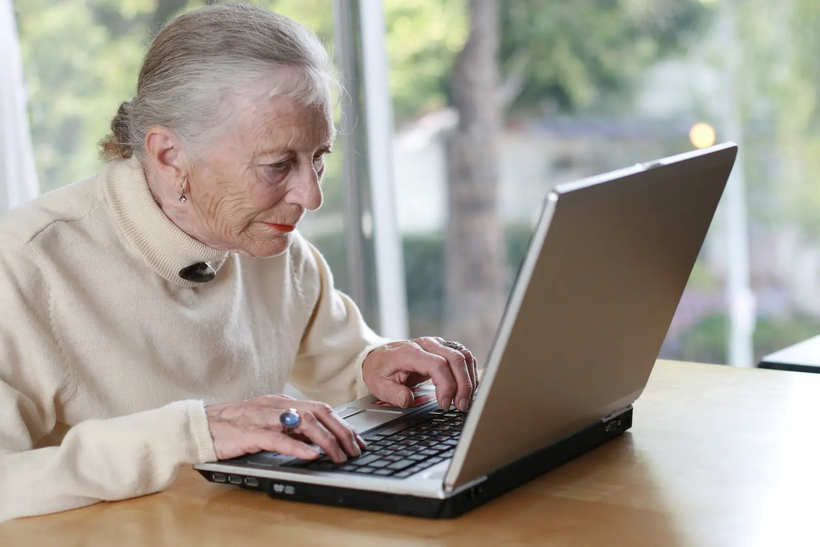 Senior woman at home sitting in front of her lap top