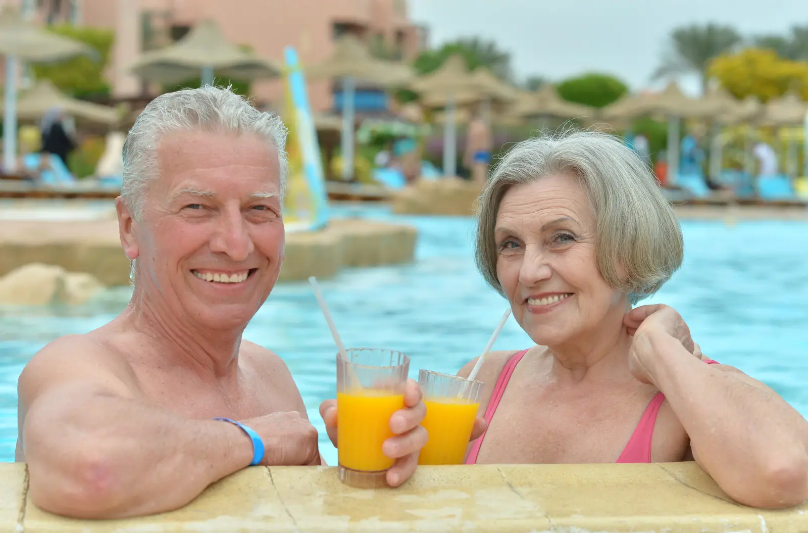 Senior couple drinking cocktails in pool at a hotel resort