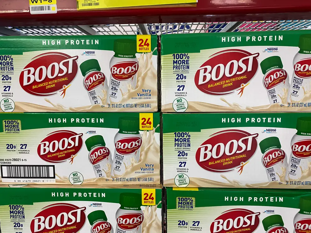 Six green boxes of Boost vanilla protein shake