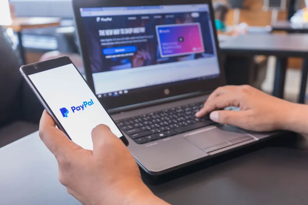 A man using PayPal on a laptop and his phone